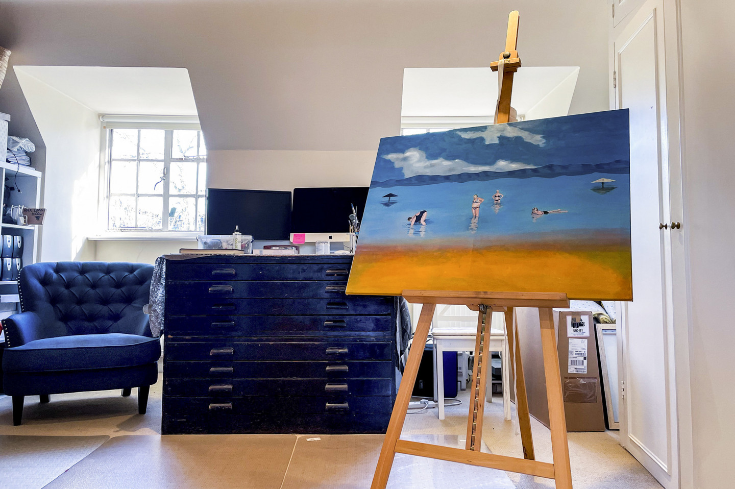 Spacious art studio with oil painted canvas on an easel. Palette windows, arm chair and drawers. Location hire for TV and filming in Park Lodge, London