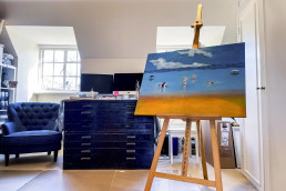 Spacious art studio with oil painted canvas on an easel. Palette windows, arm chair and drawers. Location hire for TV and filming in Park Lodge, London