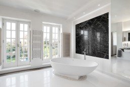 White modern bathroom with a garden view, marble decor, shutters, bathtub and good lighting. Location hire for TV and filming in Park Lodge, London
