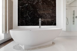 White modern bathroom with a garden view, marble decor, shutters, bathtub and good lighting. Location hire for TV and filming in Park Lodge, London
