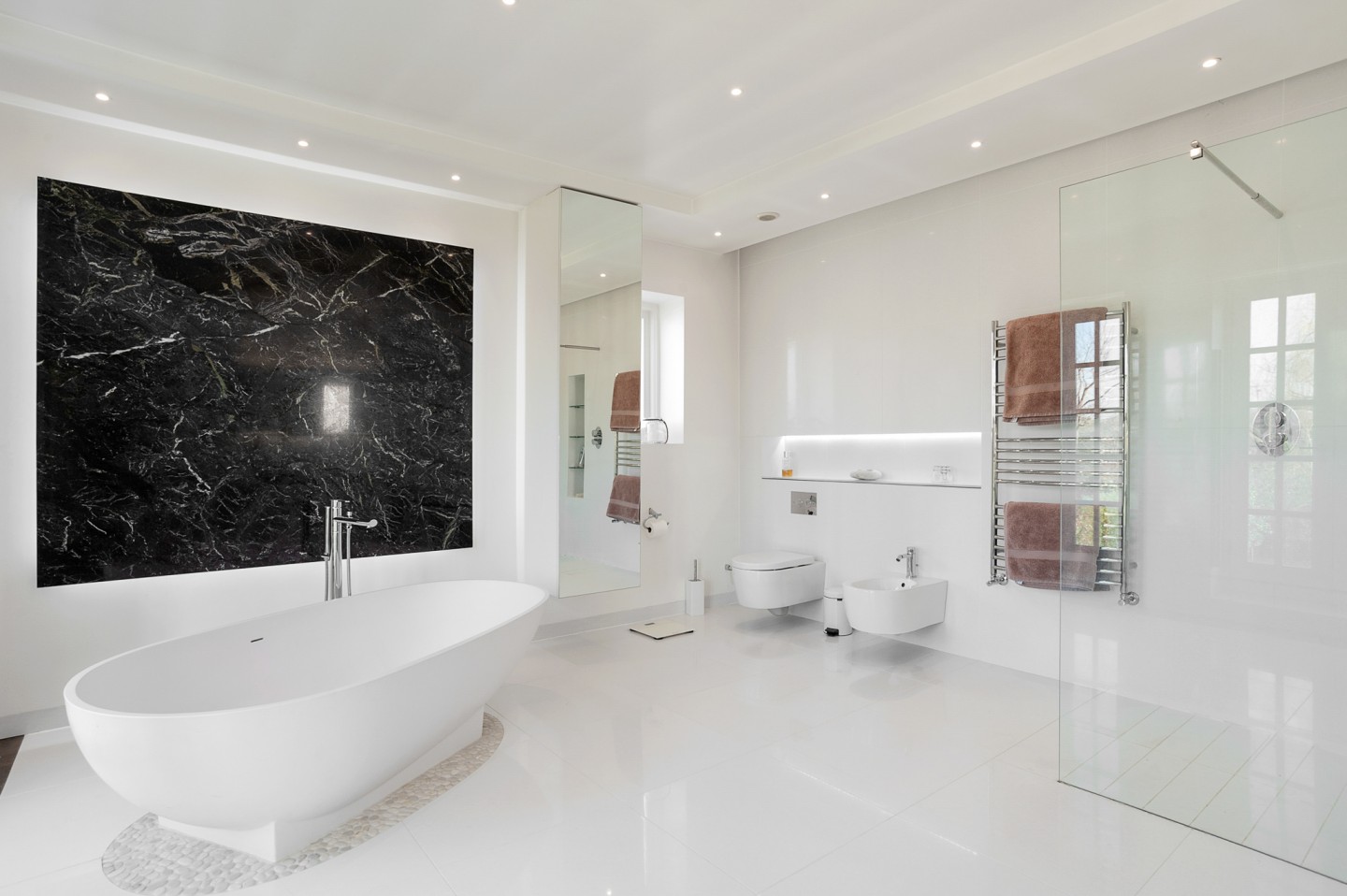 White modern bathroom with a garden view, glass shower, marble decor, shutters, bathtub and good lighting. Location hire for TV and filming in Park Lodge, London