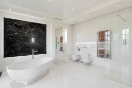 White modern bathroom with a garden view, glass shower, marble decor, shutters, bathtub and good lighting. Location hire for TV and filming in Park Lodge, London