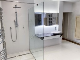 White modern bathroom with a glass shower, marble sink, shutters, mirror and good lighting. Location hire for TV and filming in Park Lodge, London