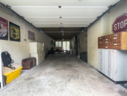 Spacious light garage with drawers and storage for bicycles, tool box and cars. Metal car posters on the wall and road signs. Location hire for TV and filming in Park Lodge, London