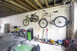 Spacious light garage with bicycles storage on wall mount. Tool box and mechanics on stone floor. Location hire for TV and filming in Park Lodge, London