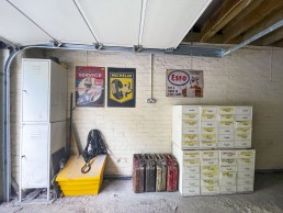 Spacious light garage with drawers and storage for bicycles, tool box and cars. Metal car posters on the wall and road signs. Location hire for TV and filming in Park Lodge, London