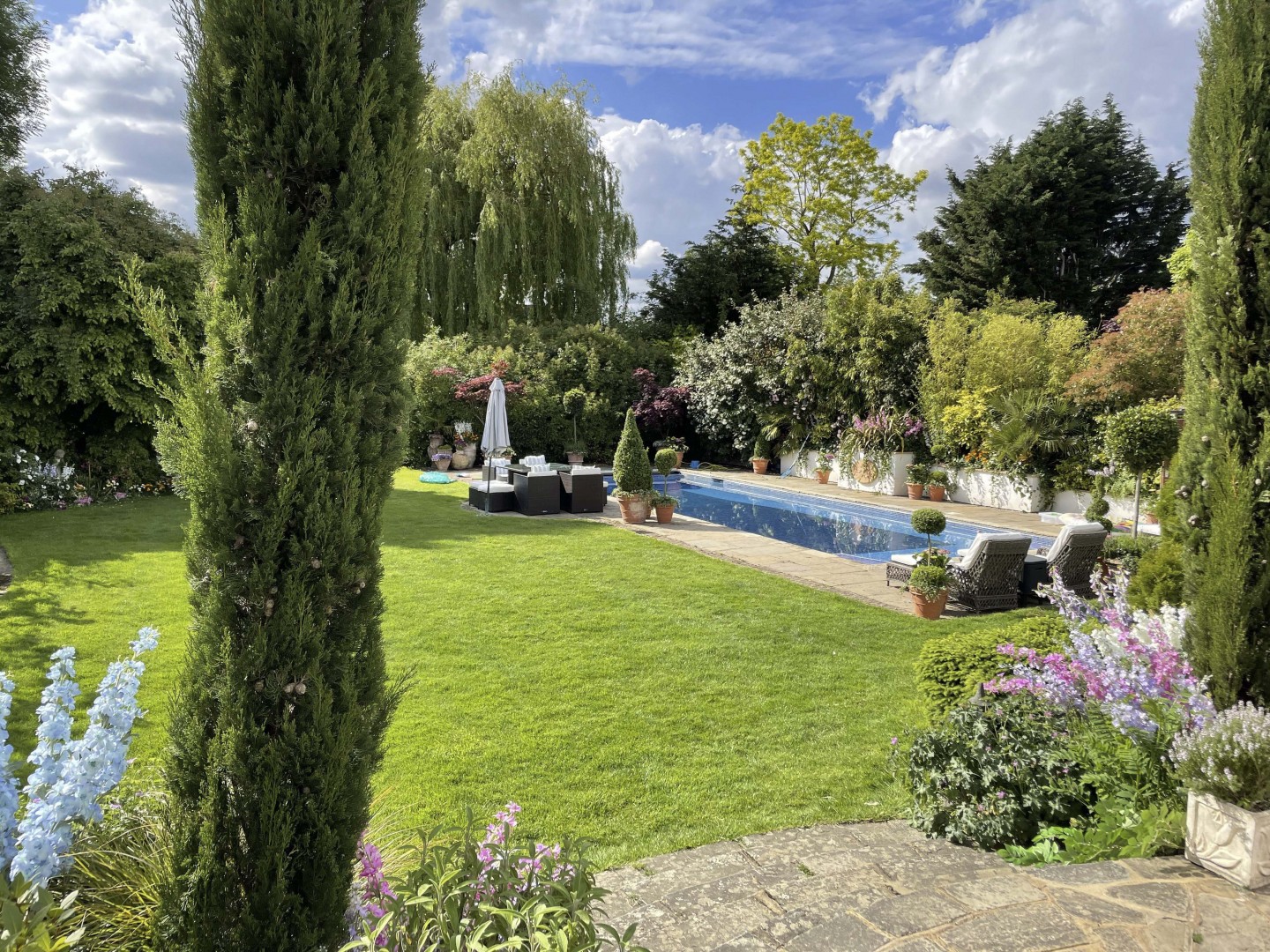 Garden with planters, swimming pool, trees flowers and outdoor furniture. Location hire for TV and filming in Park Lodge, London