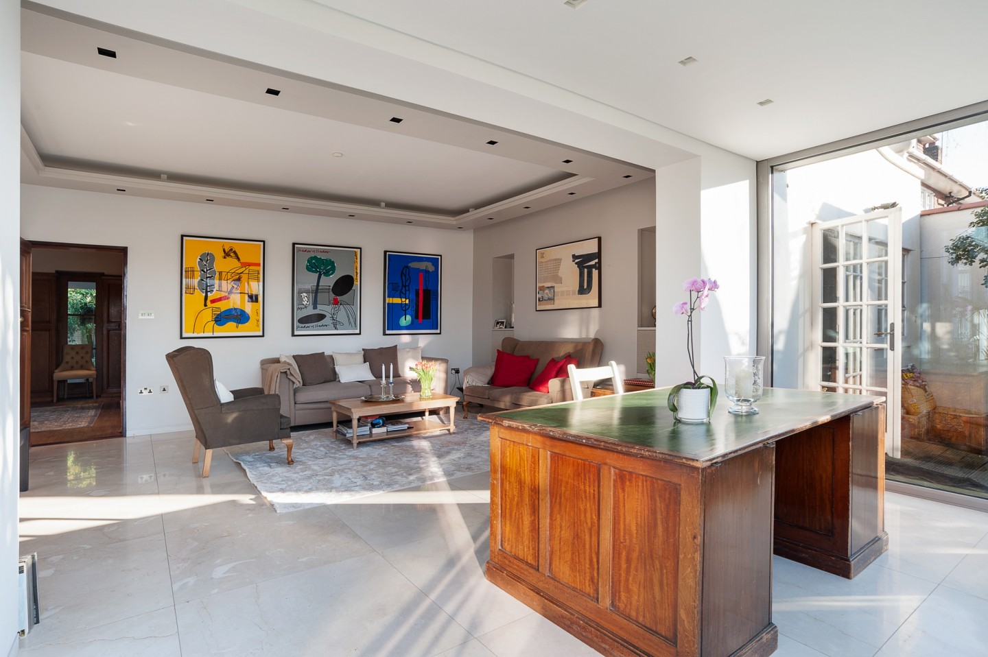 Large sitting room with oak desk and marble floor with bifold glass window. Location hire for TV and filming in Park Lodge, London