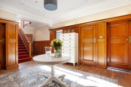 Luxurious entrance hall with large staircase and centrepiece table on oak flooring. Location hire for TV and filming in Park Lodge, London