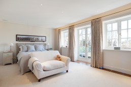 Master bedroom modern cream sofa and double bed with bedsides and a terrace overlooking the garden. Location hire for TV and filming in Park Lodge, London