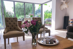 Sitting room with glass doors and marble floor. Flower centrepiece on coffee table and armchair. Location hire for TV and filming in Park Lodge, London