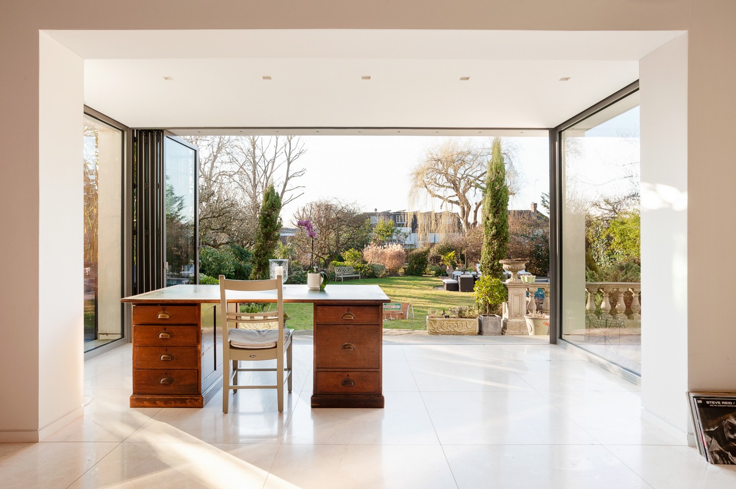 Sitting room with a garden view, glass door, work table and marble floor. Location hire for TV and filming in Park Lodge, London