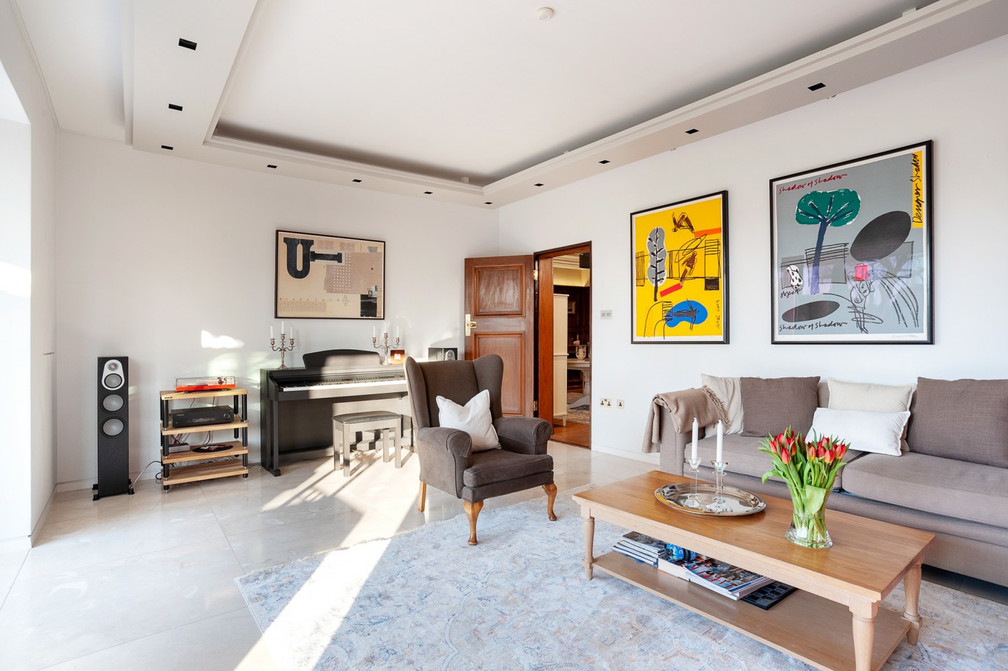 Sitting room with a garden view, modern art on wall, piano, stereo and marble floor. Location hire for TV and filming in Park Lodge, London