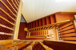 Staircase bannister with oak panels and acorn windows in bright lighting. Location hire for TV and filming in Park Lodge, London