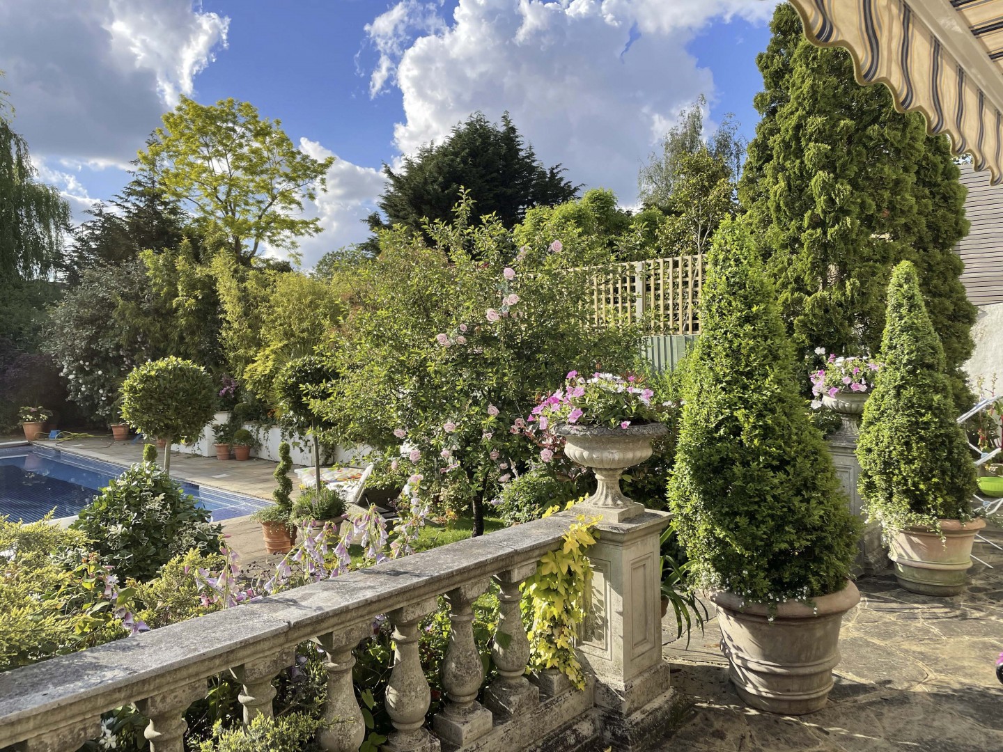 Terracotta balustrade terrace garden with planters, swimming pool, trees. Location hire for TV and filming in Park Lodge, London