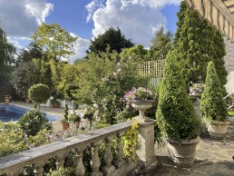 Terracotta balustrade terrace garden with planters, swimming pool, trees. Location hire for TV and filming in Park Lodge, London