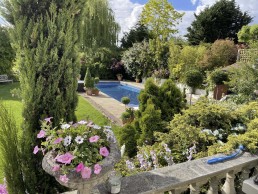 Terracotta balustrade terrace garden with planters, swimming pool and trees. Location hire for TV and filming in Park Lodge, London
