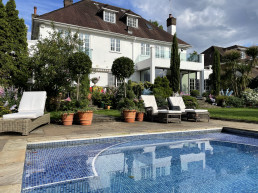 Terracotta balustrade terrace garden with planters, swimming pool and trees. Location hire for TV and filming in Park Lodge, London