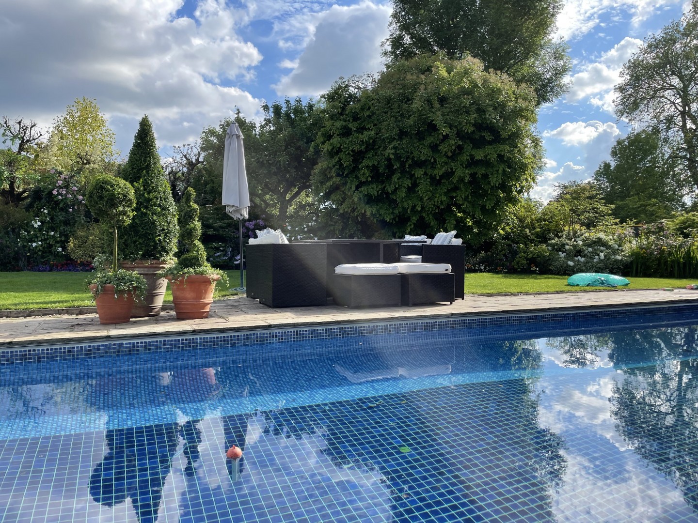 Terracotta balustrade terrace garden with planters, swimming pool and trees. Location hire for TV and filming in Park Lodge, London