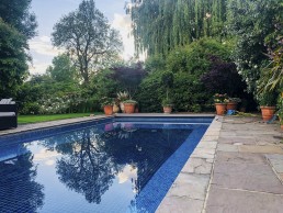Terracotta garden with planters, swimming pool, outdoor furniture and trees. Location hire for TV and filming in Park Lodge, London