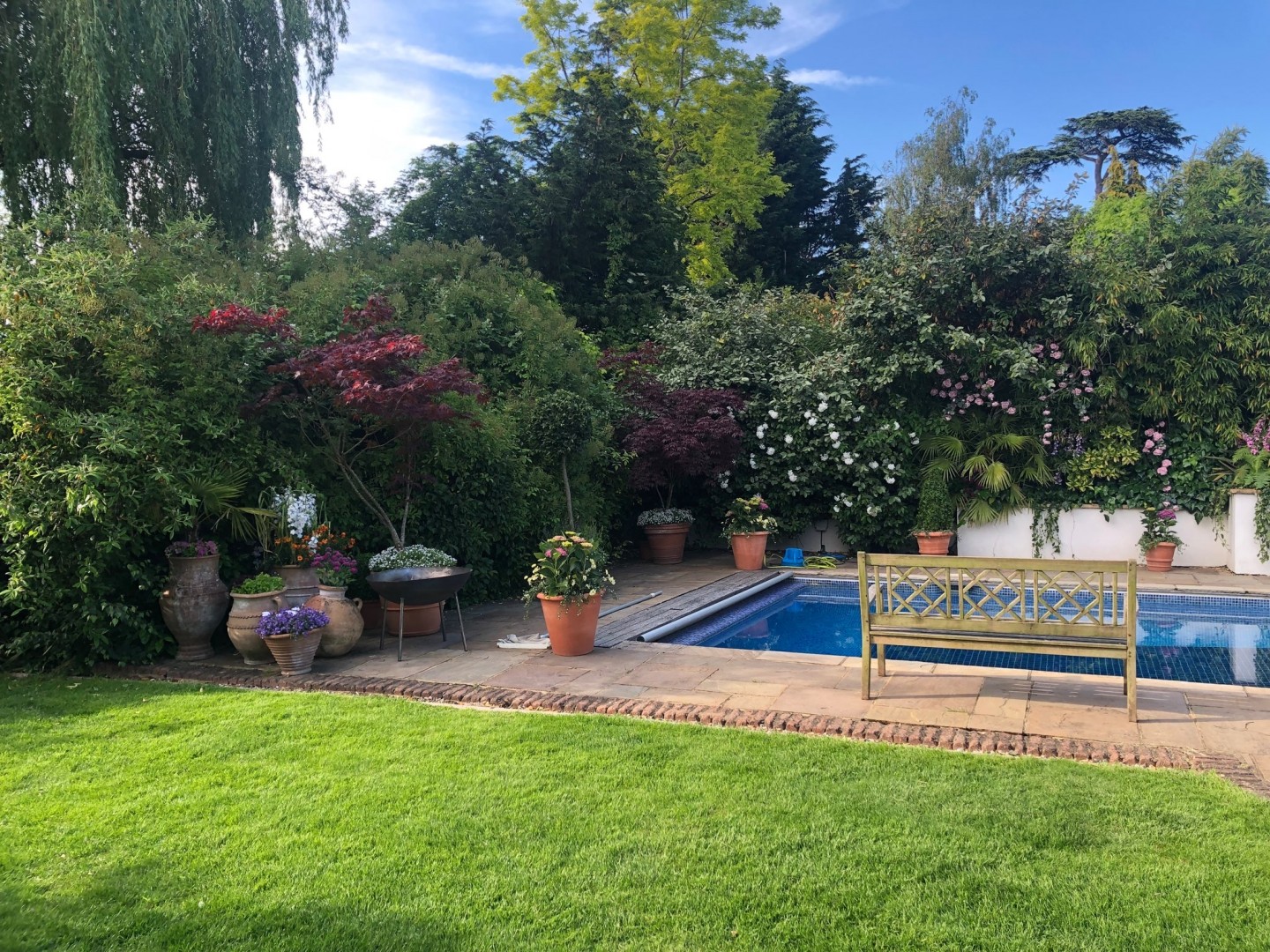Terracotta garden with bench, flowers, planters, and trees. Location hire for TV and filming in Park Lodge, London