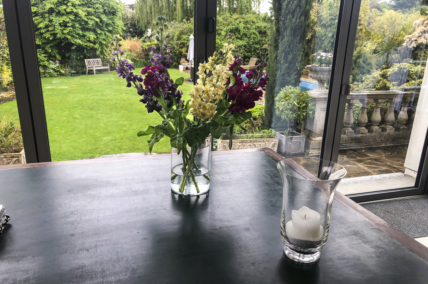 Writing desk with beautiful flower vase and candle. Garden view through the glass doors. Location hire for TV and filming in Park Lodge, London